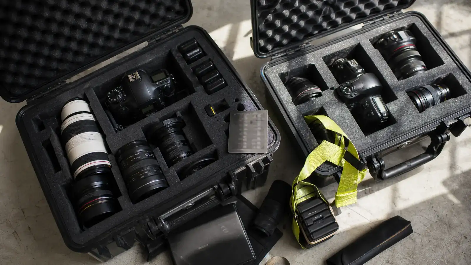 Flat-lay of camera cases packed in foam with a yellow luggage strap around one case